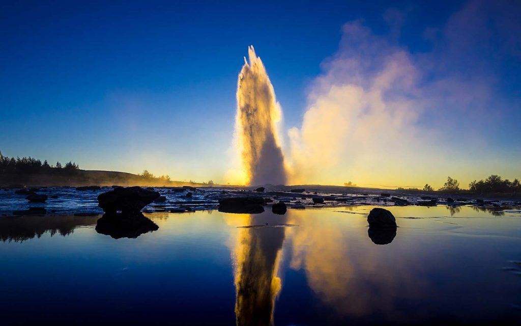 Strokkur geyser erupting at sunset in the Golden Circle, Iceland