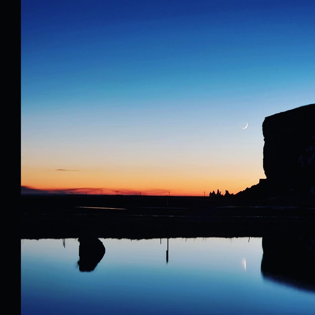 Reynisdrangar Sea stacks at sunset near Vík with the moon reflected in the water, Iceland